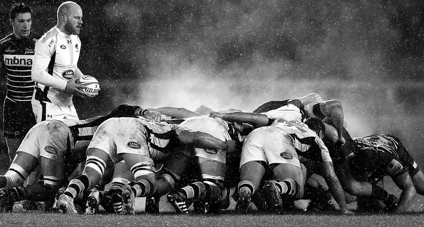 Formación de rugby avanzando en conjunto sobre el campo bajo la lluvia