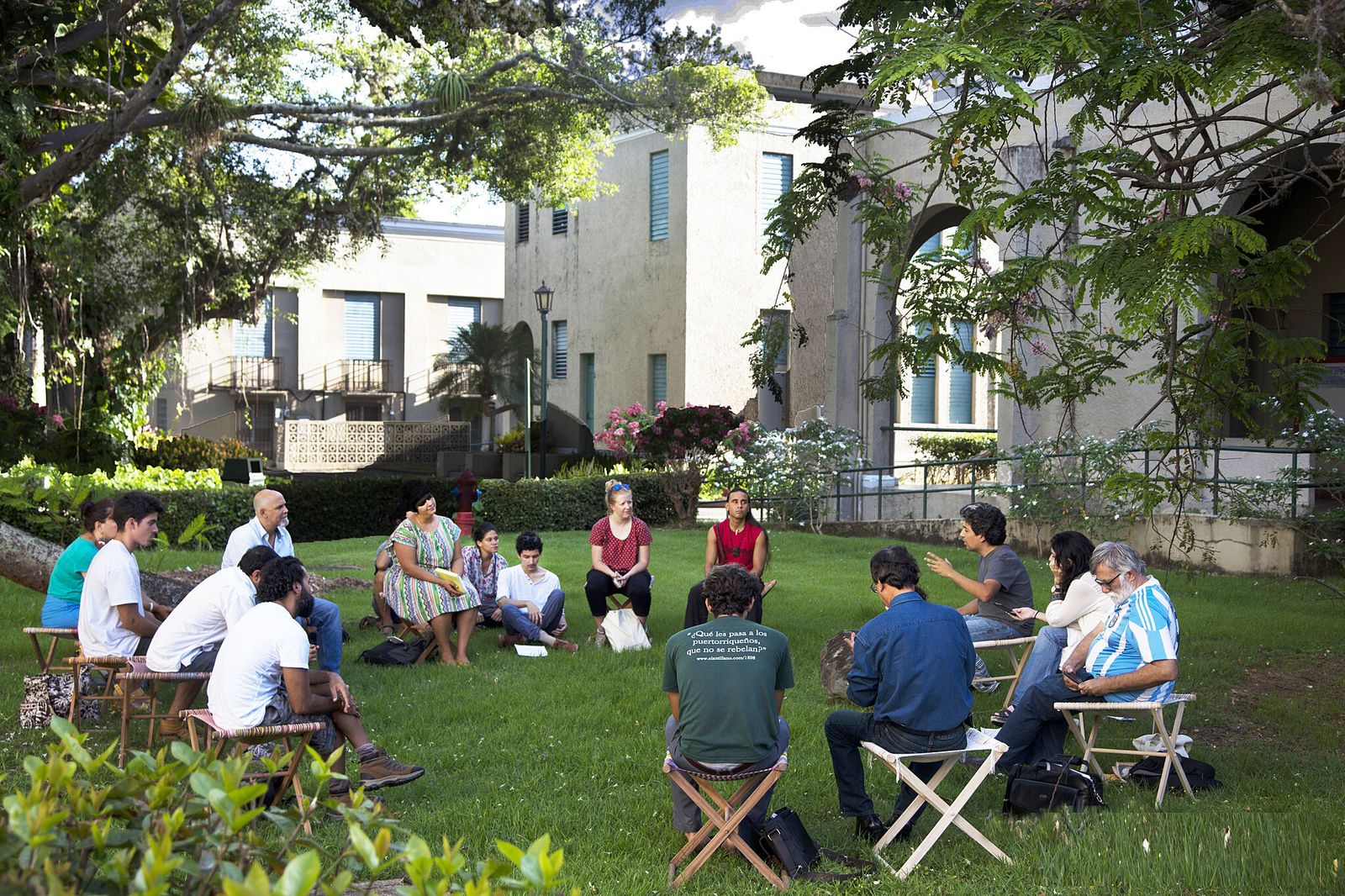 Grupo de personas conversando sentadas en círculo al aire libre en un jardín